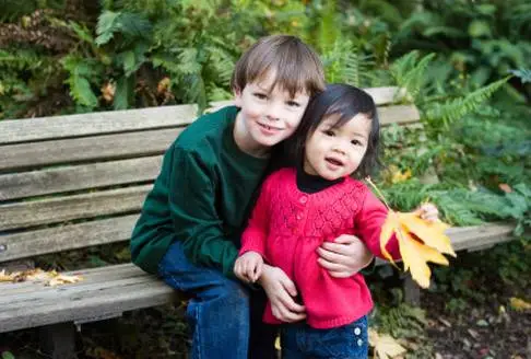 Adoptive siblings play outside sitting at a bench