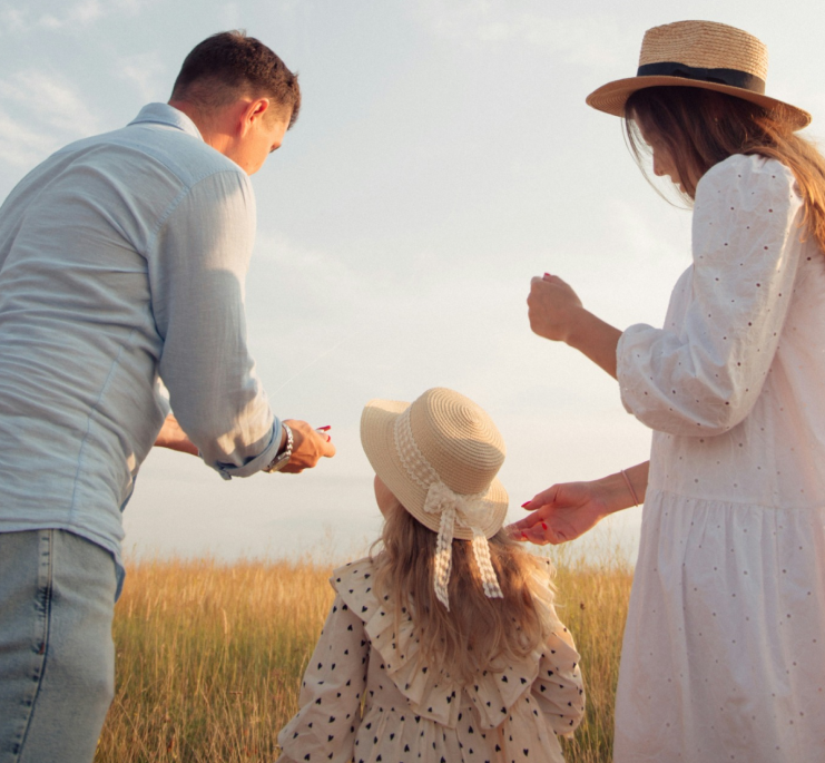 Mom, dad and adoptive daughter watch the sunset together