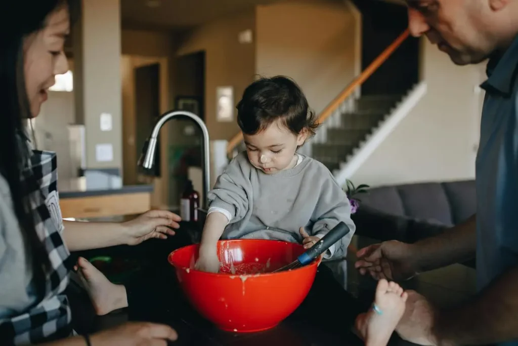 Kid plays with empty bowl of food while adoptive parents watch